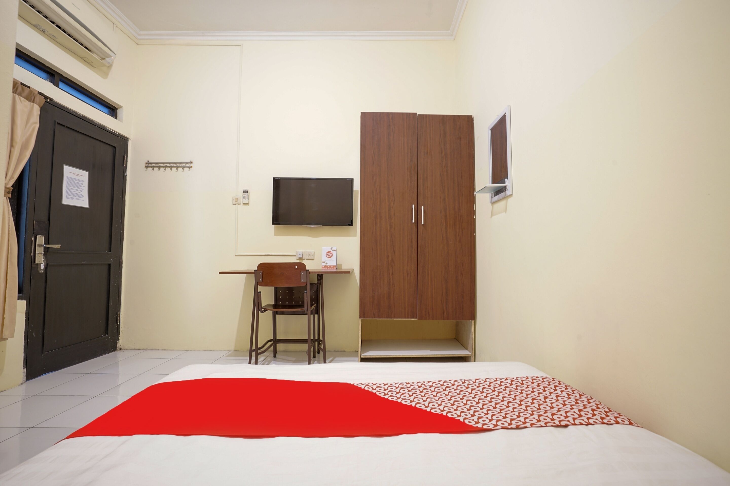 A hotel room with a bed, a desk with a chair, a TV, and a wardrobe.