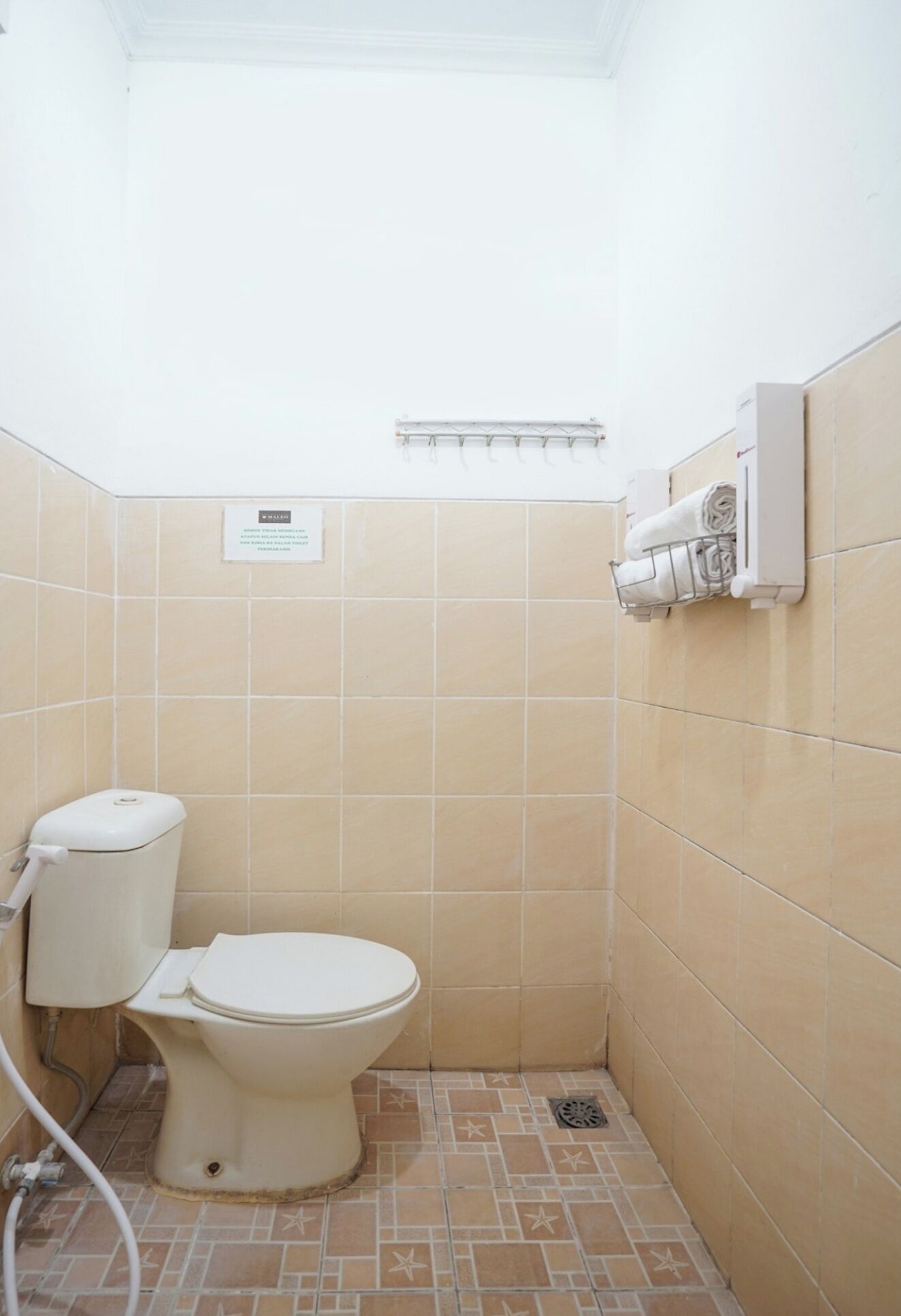 A small, tiled bathroom with a toilet, a towel rack, and a wall-mounted air conditioning unit.