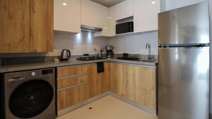 A modern kitchen with wooden cabinets, stainless steel appliances, and a built-in washing machine. - w* | Divine 2BR with Majestic Deco in Barranco (Barranco)