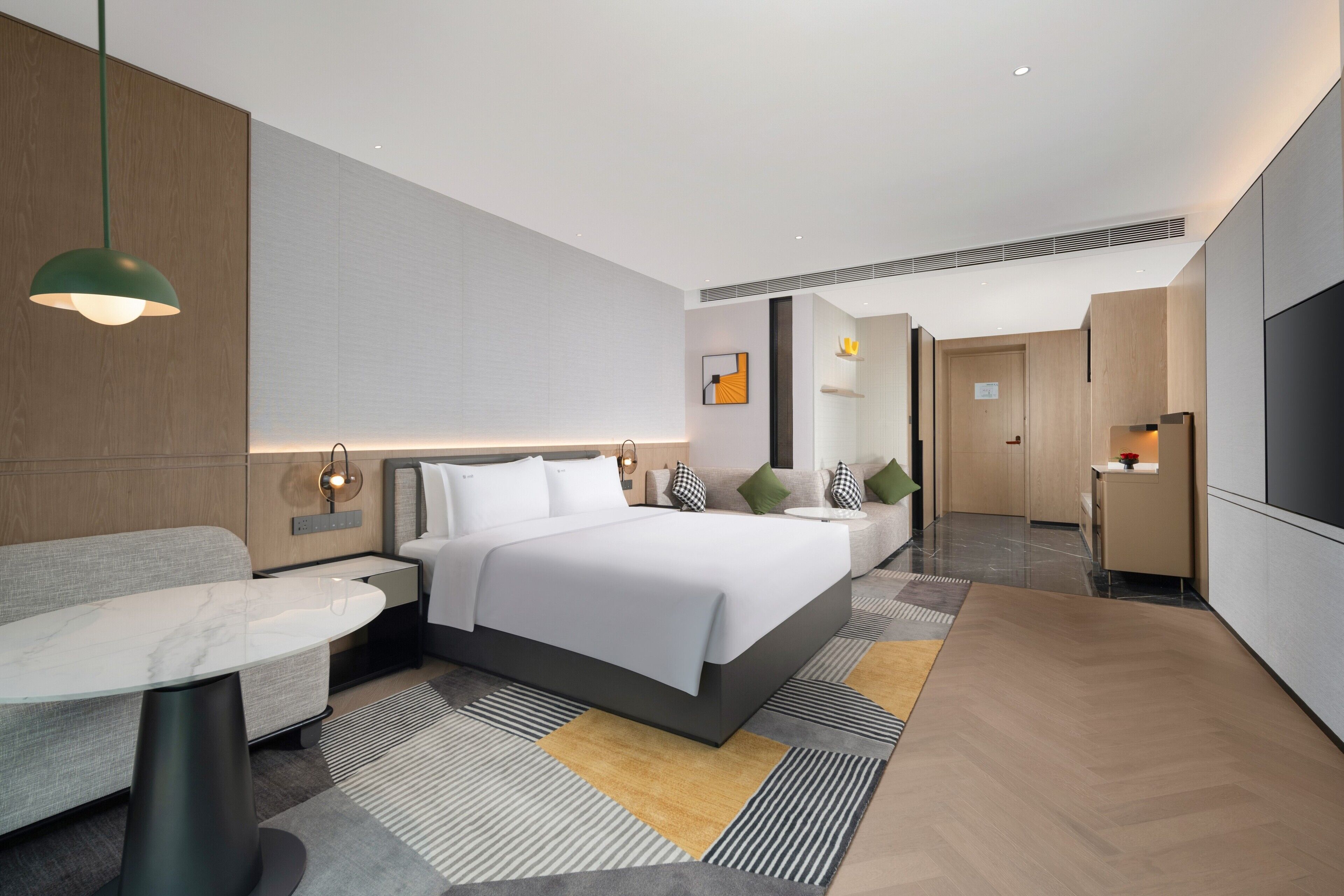 Una habitación de hotel moderna con una cama grande, mesitas de noche, un escritorio y un televisor.
