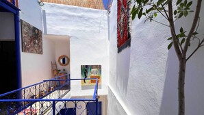 A narrow alleyway with a white wall, a blue metal staircase, and a tree.