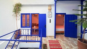 A courtyard with a blue staircase, a bed, and a door leading to a room.