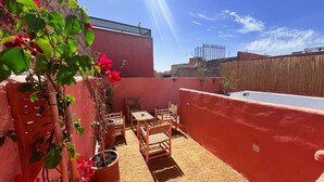 A rooftop patio with outdoor furniture, potted plants, and a view of the city skyline.
