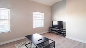 A living room with a TV on a stand, two windows, and a coffee table. - Charming 1 Bedroom Apartment in Central Liverpool (Liverpool)