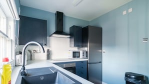 A modern kitchen with a stainless steel sink, a microwave, and a refrigerator. - Charming 1 Bedroom Apartment in Central Liverpool (Liverpool)