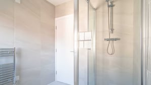 A modern bathroom with a glass shower enclosure, a towel rack, and a door. - Charming 1 Bedroom Apartment in Central Liverpool (Liverpool)