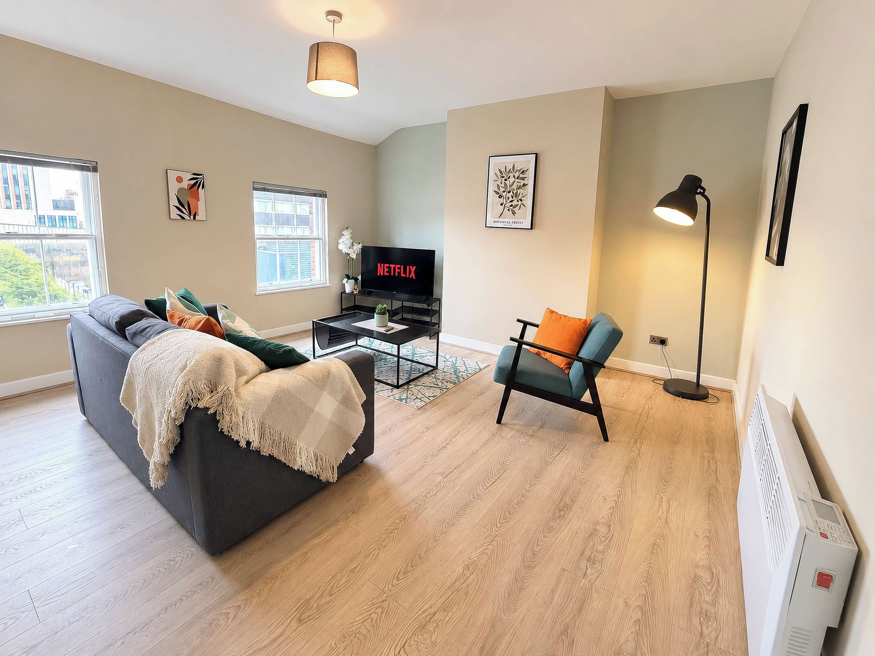 Un salon moderne avec un canapé, une table basse, un téléviseur et une lampe sur pied.