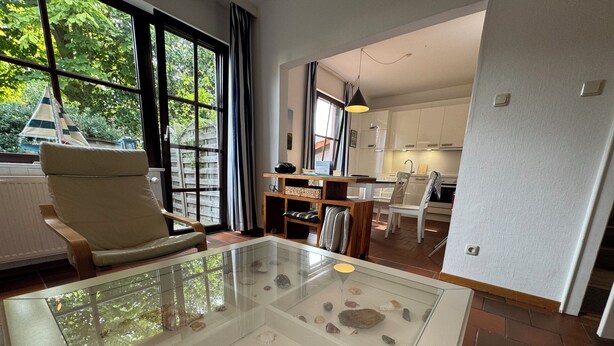 A living room with a glass display case containing various shells and a chair. - Experience Frisian coziness in Haus Siril and the Kombüse apartment on Wangerooge (Wangerooge)