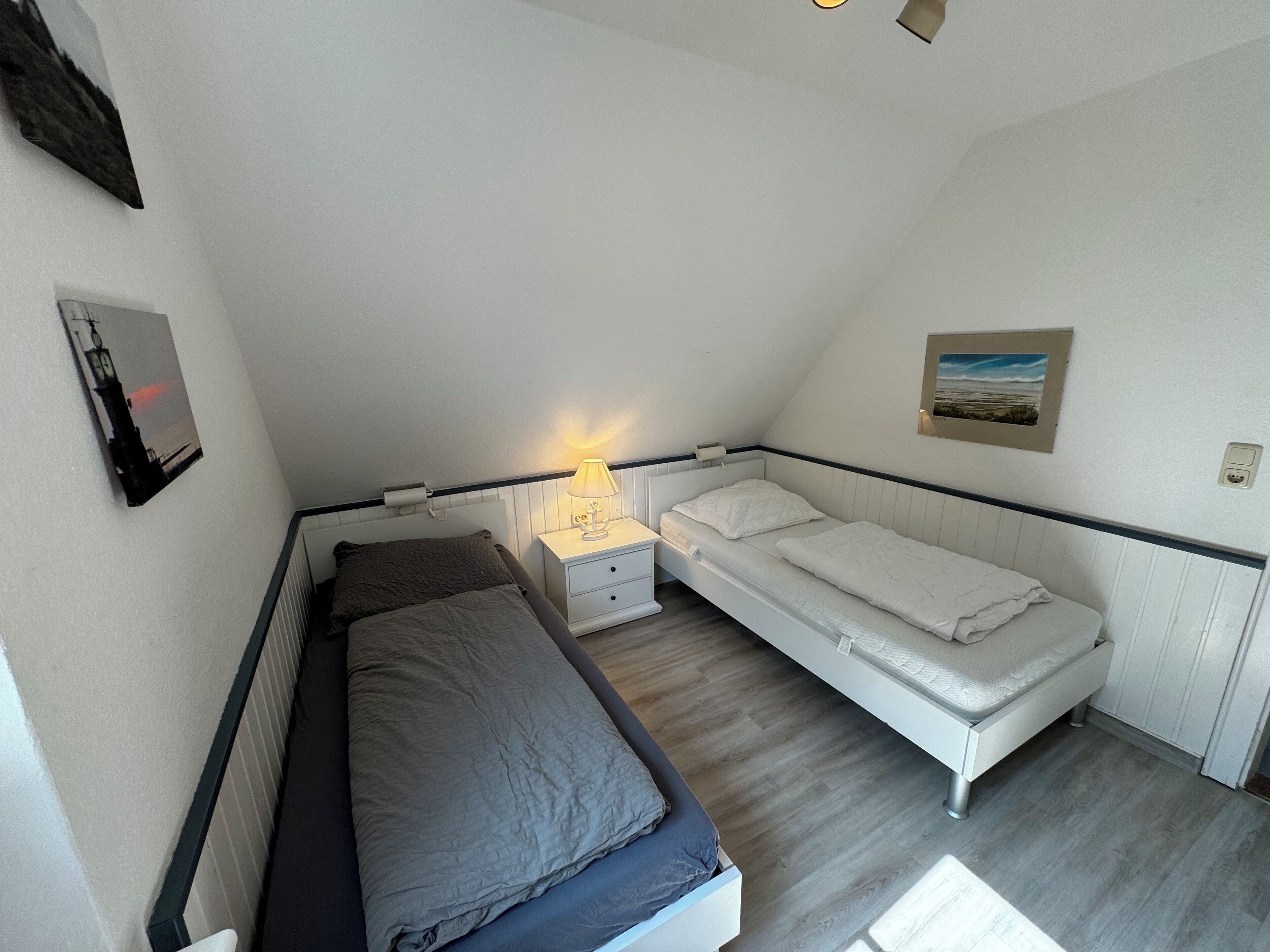 Ein kleines Schlafzimmer mit einem Bett, einem Nachttisch, einer Lampe und einem Bild an der Wand.