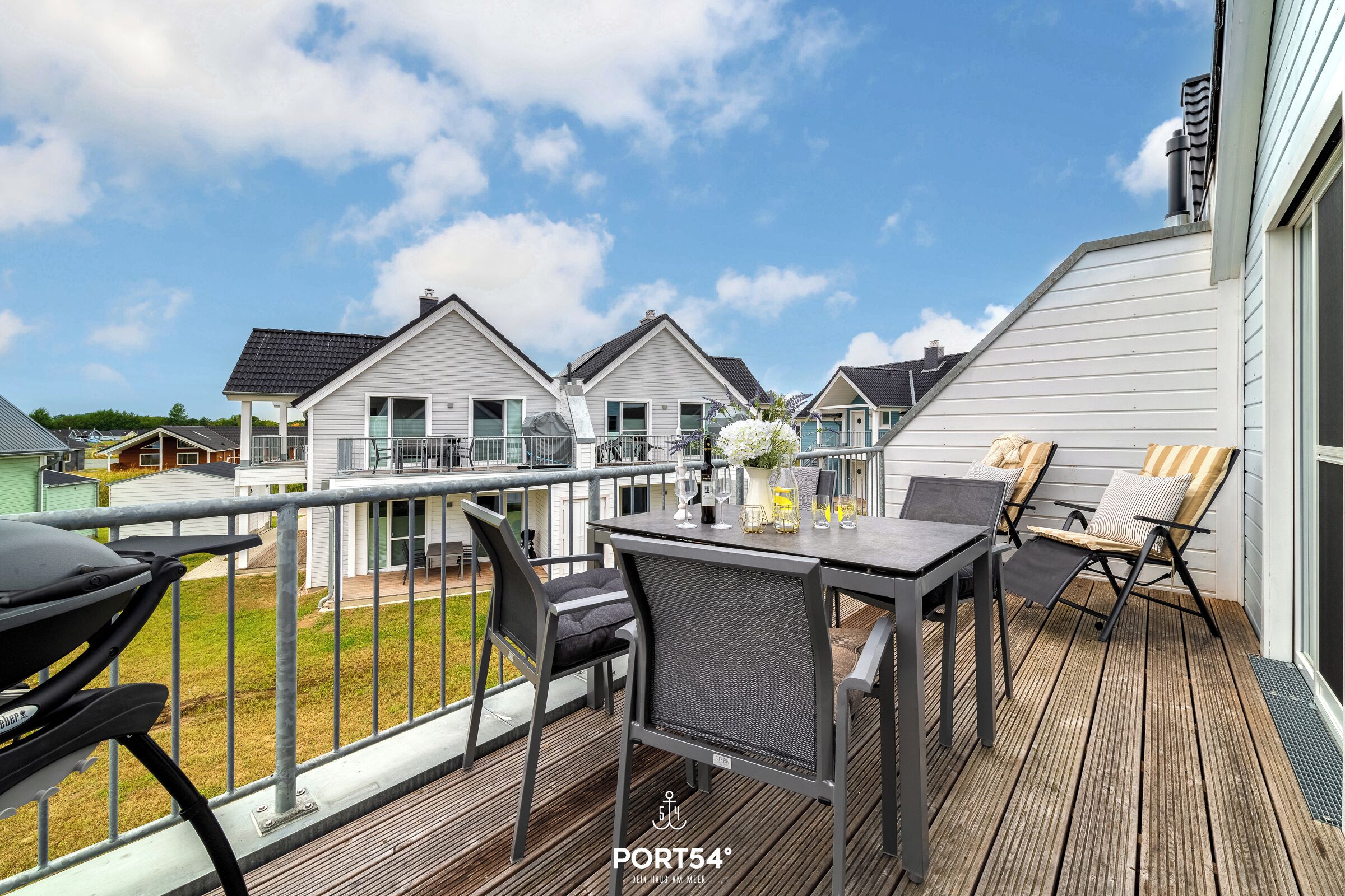 A deck with a table and chairs, overlooking a residential area with houses.