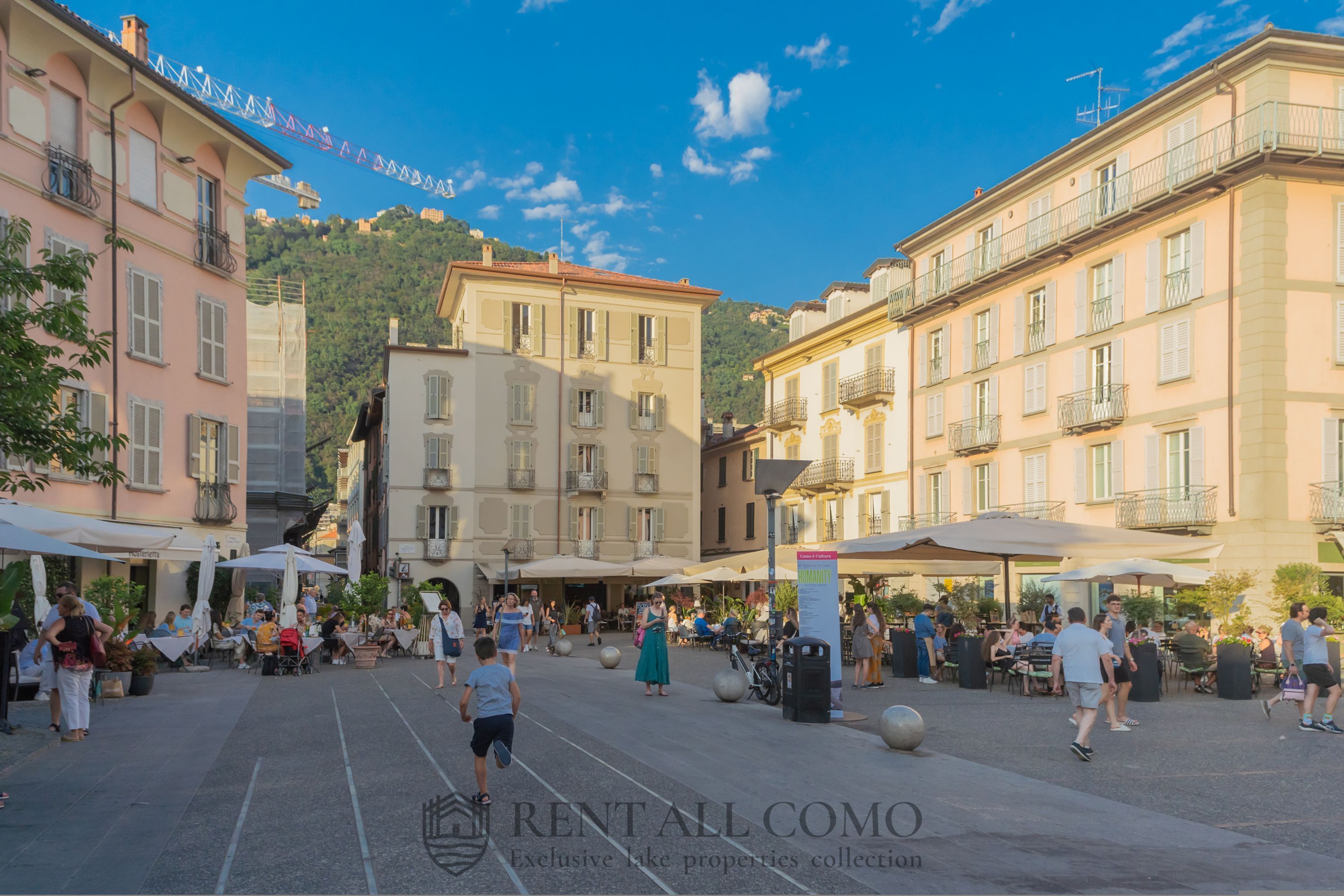 A bustling outdoor café area with outdoor seating and a clear sky.