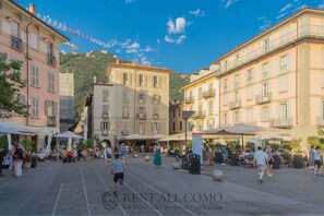 Un espace de café extérieur animé, avec des tables et des chaises en plein air, et un ciel dégagé.