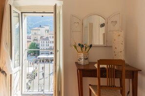 Une pièce avec un bureau en bois, une chaise, un miroir orné de découpes en forme de cœur et une vue sur le paysage urbain par la fenêtre.
