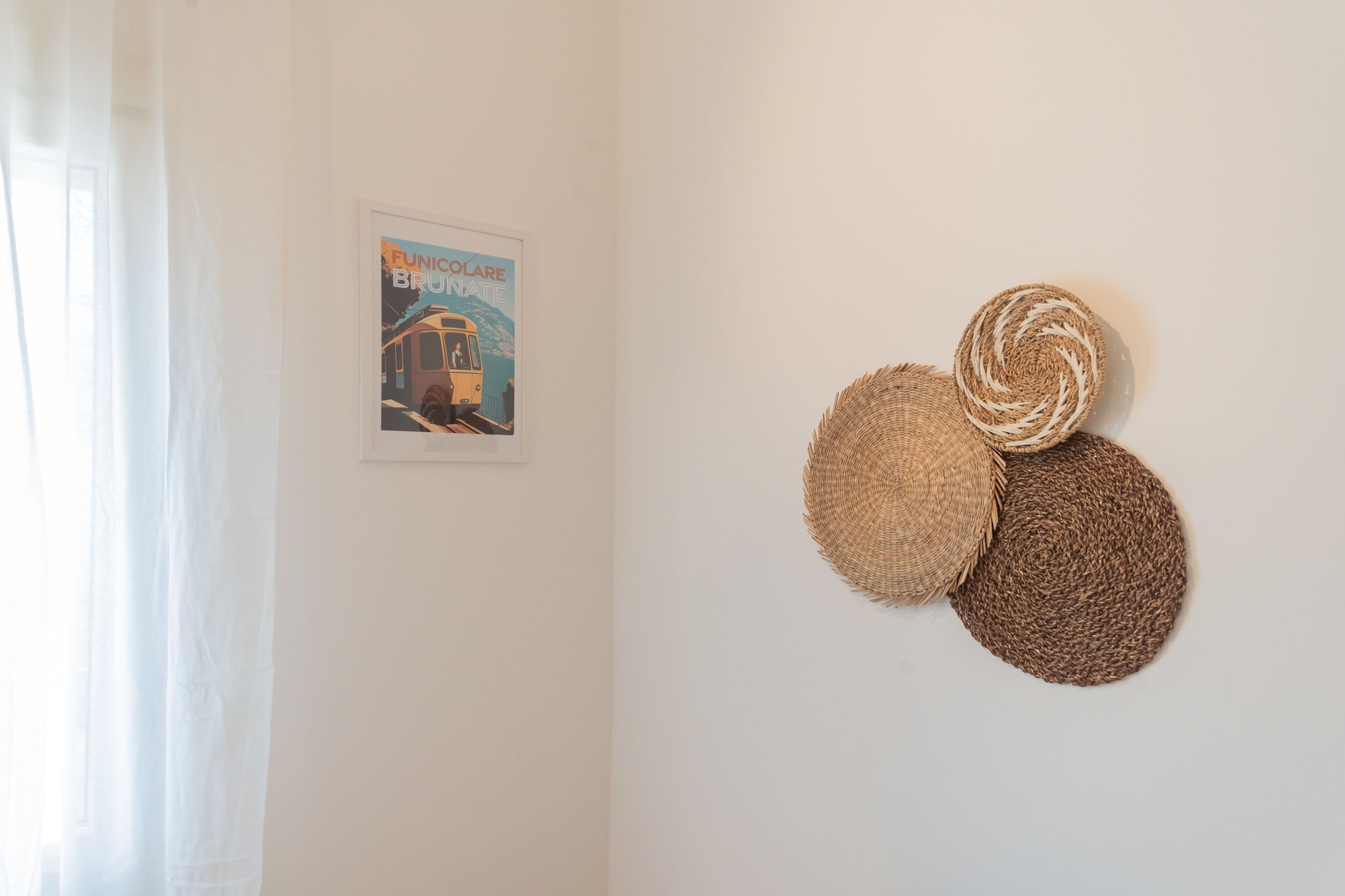 A wall with a framed poster and three woven wall hangings.