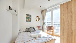 Une chambre à coucher avec un lit, une chaise, une fenêtre et un tableau accroché au mur.