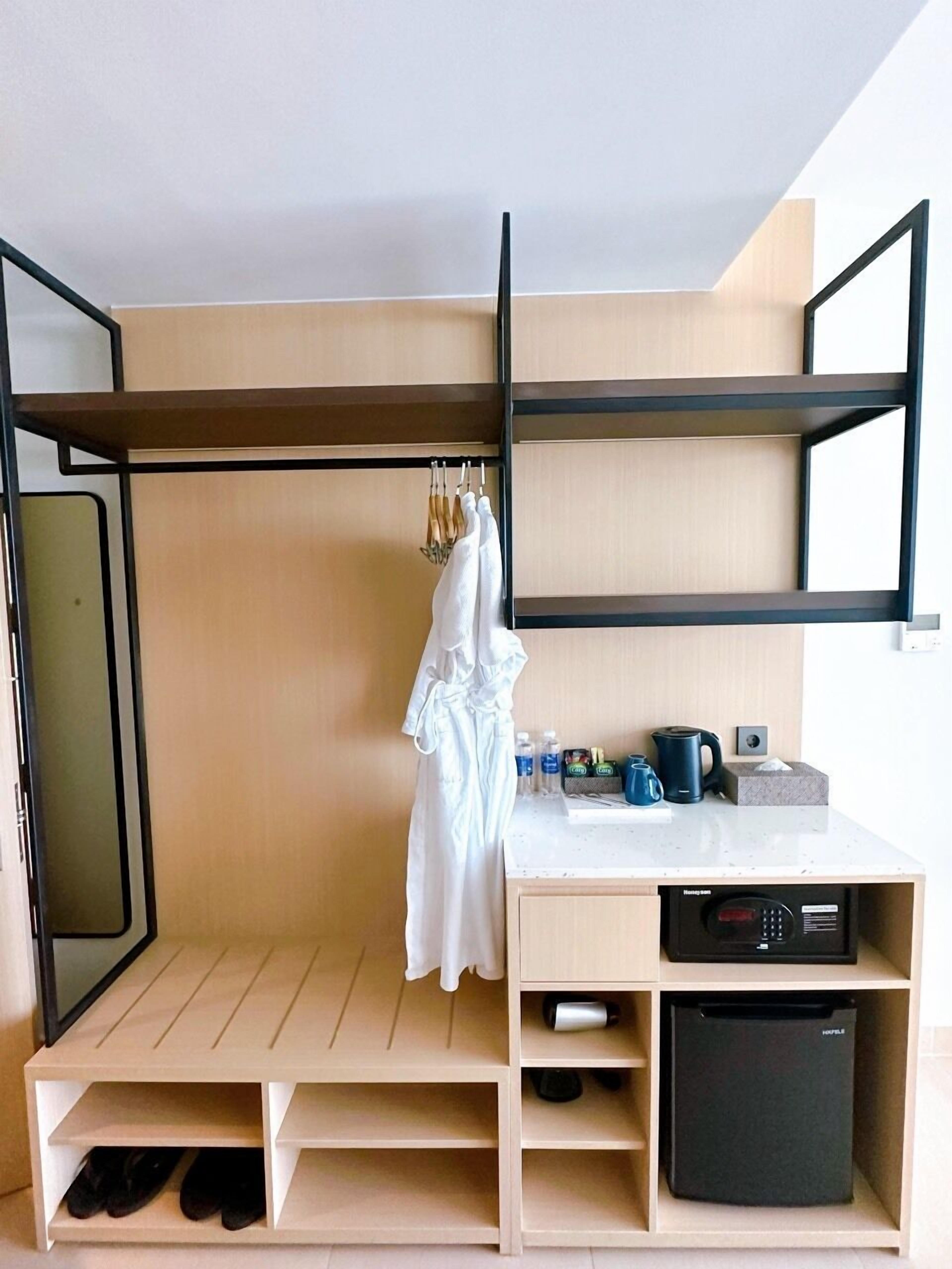 Ein kleines Zimmer mit Etagenbett, einer kleinen Küchenzeile, einem Schuhregal und einem Kleiderhaken.