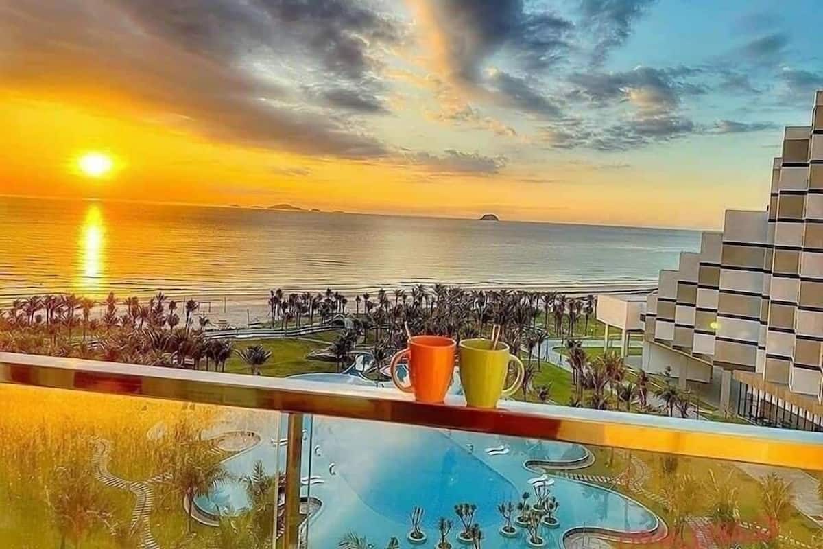 Vista al capvespre des d'un balcó amb piscina i palmeres.
