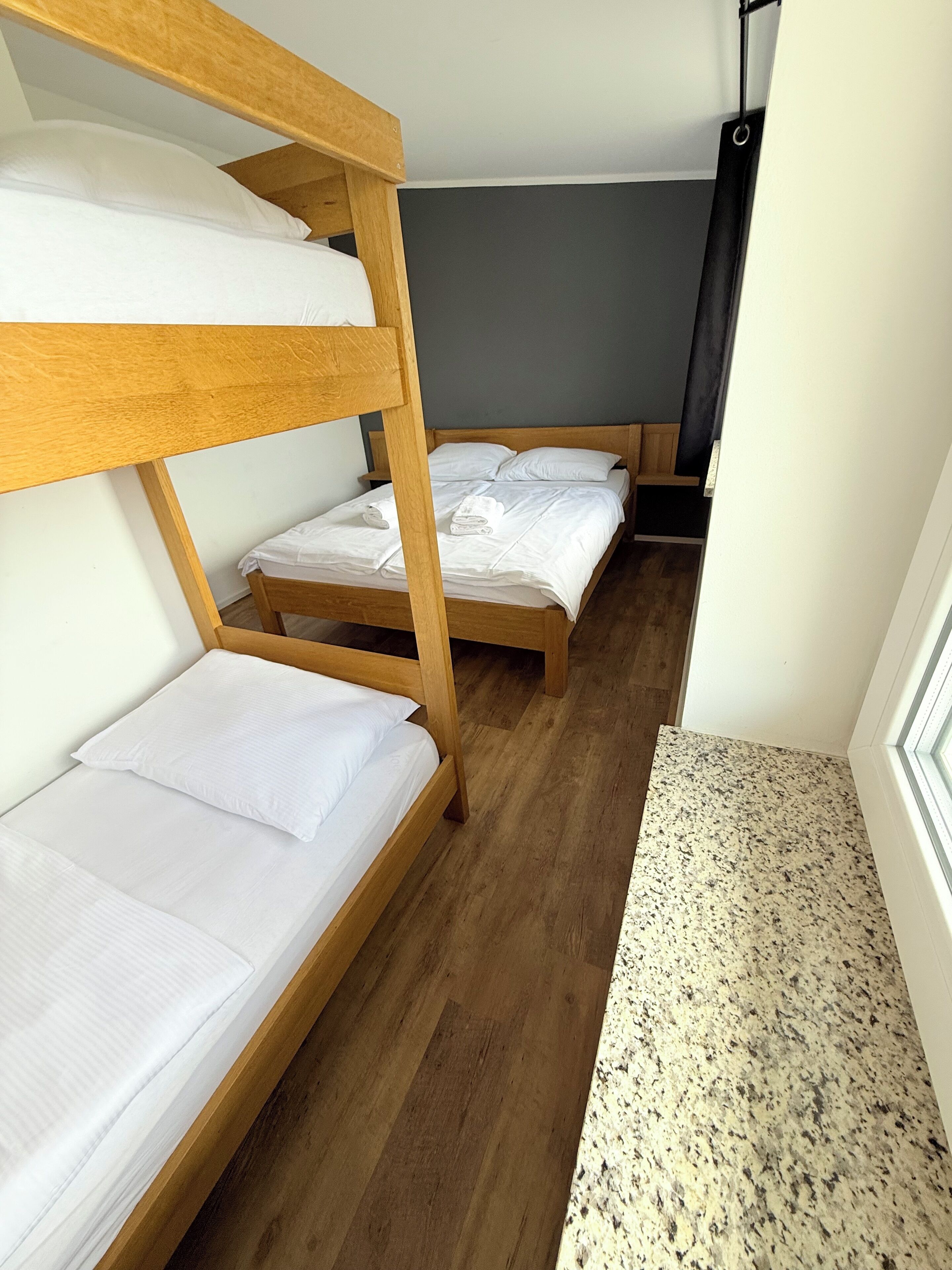 Ein Zimmer mit zwei Etagenbetten, Holzboden und einem Fenster mit Blick nach draußen.