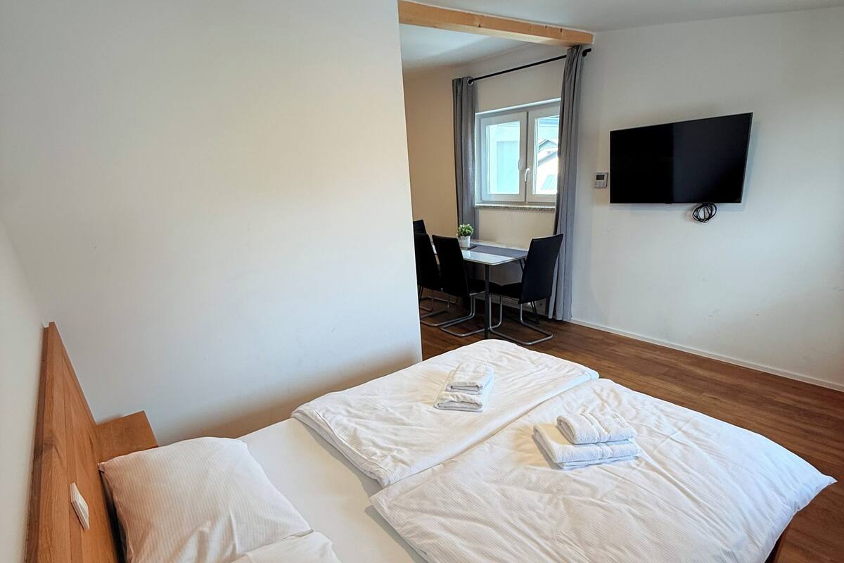 A hotel room with a bed, a desk, and a TV.