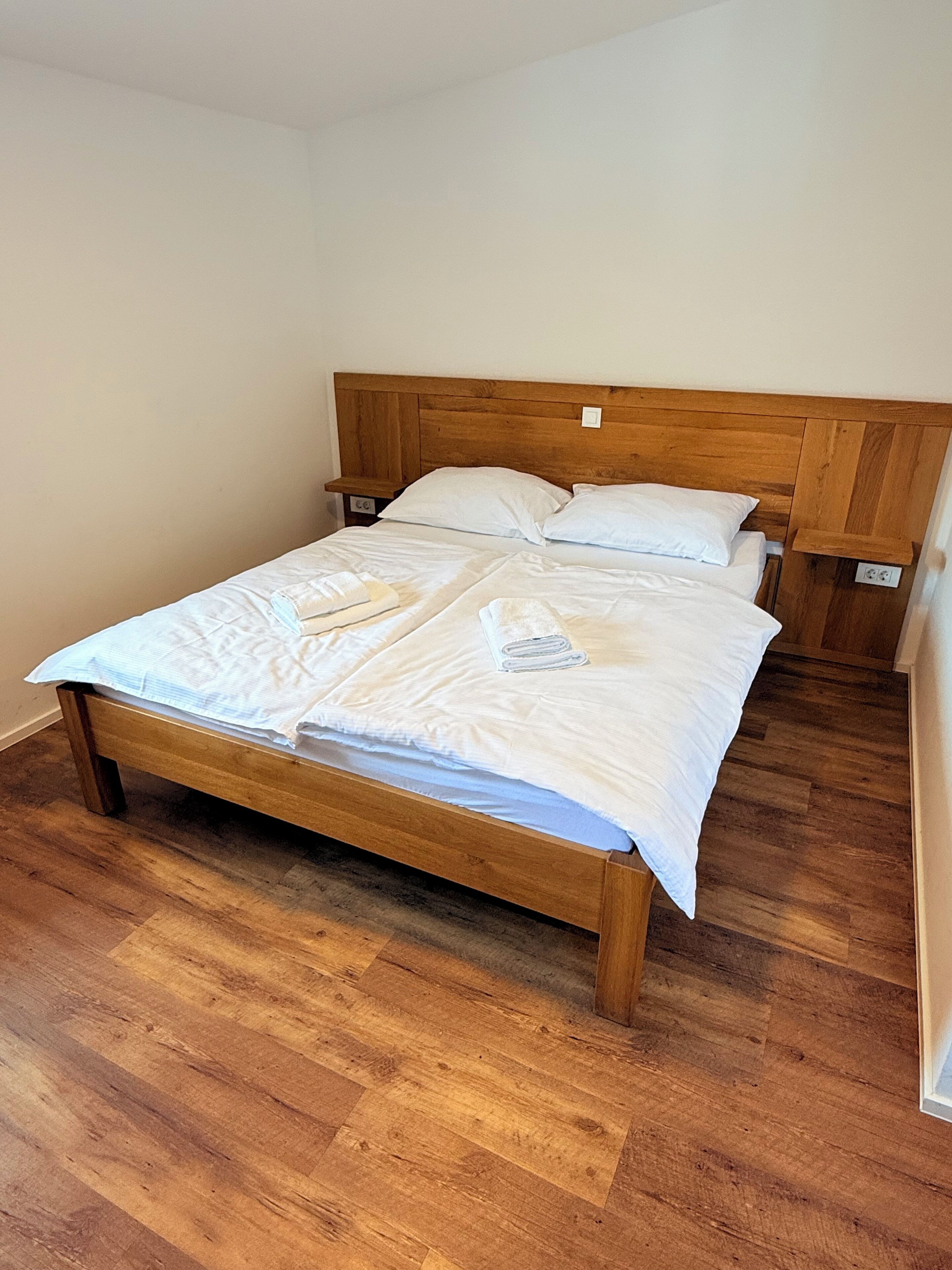 A single bed with a wooden headboard in a room with wooden flooring.