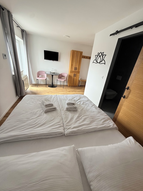 A hotel room with a bed, two chairs, a wooden wardrobe, and a TV on the wall. - PJ Hotel Cerklje - 5min to Airport - Free Parking (Cerklje na Gorenjskem)