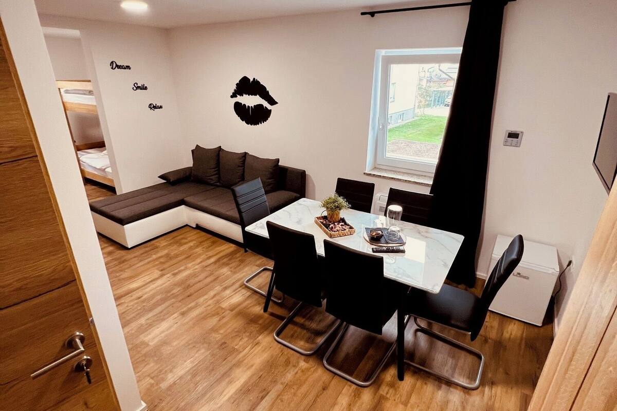 A modern living space with a dining area, a sofa, and a window with a view.