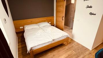 A modern bedroom with a wooden bed, a dark wall, and a wardrobe with a sliding door.