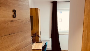 A modern room with a wooden wall, a desk, a chair, and a window with a curtain.