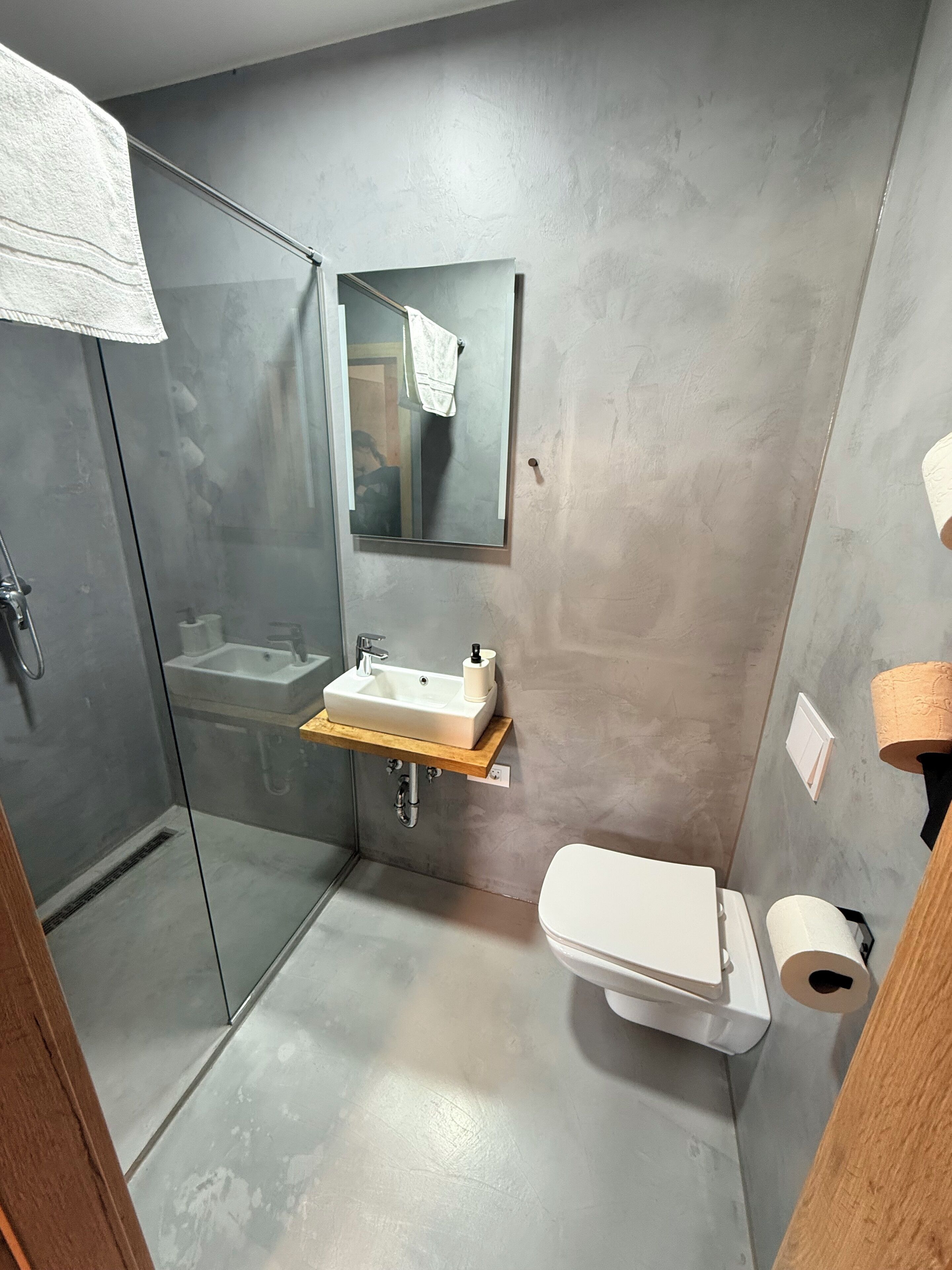 Un baño moderno con cabina de ducha de vidrio, un lavabo blanco y un inodoro.