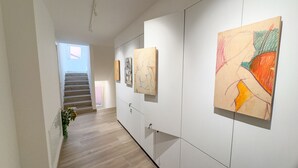 A hallway with a staircase, white walls, and artwork displayed on the walls. - Ca de la Corona - Ipnosi by Ca-sa Check (Chioggia)