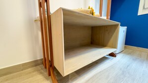 A wooden shelf unit with a flat top and a lower shelf, positioned against a wall with a blue accent. - Ca de la Corona - Ipnosi by Ca-sa Check (Chioggia)
