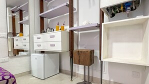 A compact kitchen with white cabinets, a small refrigerator, and a wooden stool.