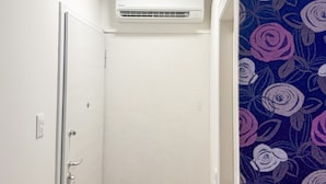 A narrow hallway with a white door, a white wall, and a ceiling-mounted air conditioner.