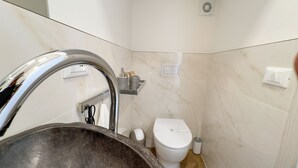 Ein Badezimmer mit Marmorwaschbecken, Toilette und Ablage für Toilettenartikel.