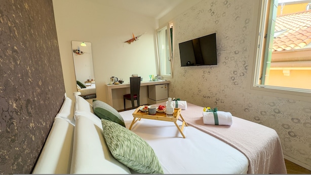 Ein Hotelzimmer mit Bett, Schreibtisch, Stuhl, Fernseher und Fenster.