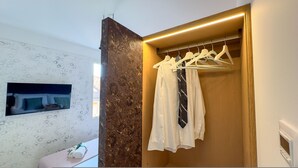 Ein Hotelzimmer mit Kleiderschrank, Spiegel und Wandfernseher.