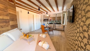 Una sala acogedora con un sofá, una mesa de comedor para dos personas y una cocina al fondo.