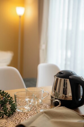 Ein Hotelzimmer mit Tee-Auffahrt, inklusive Wasserkocher, Gläsern und einer Pflanze.