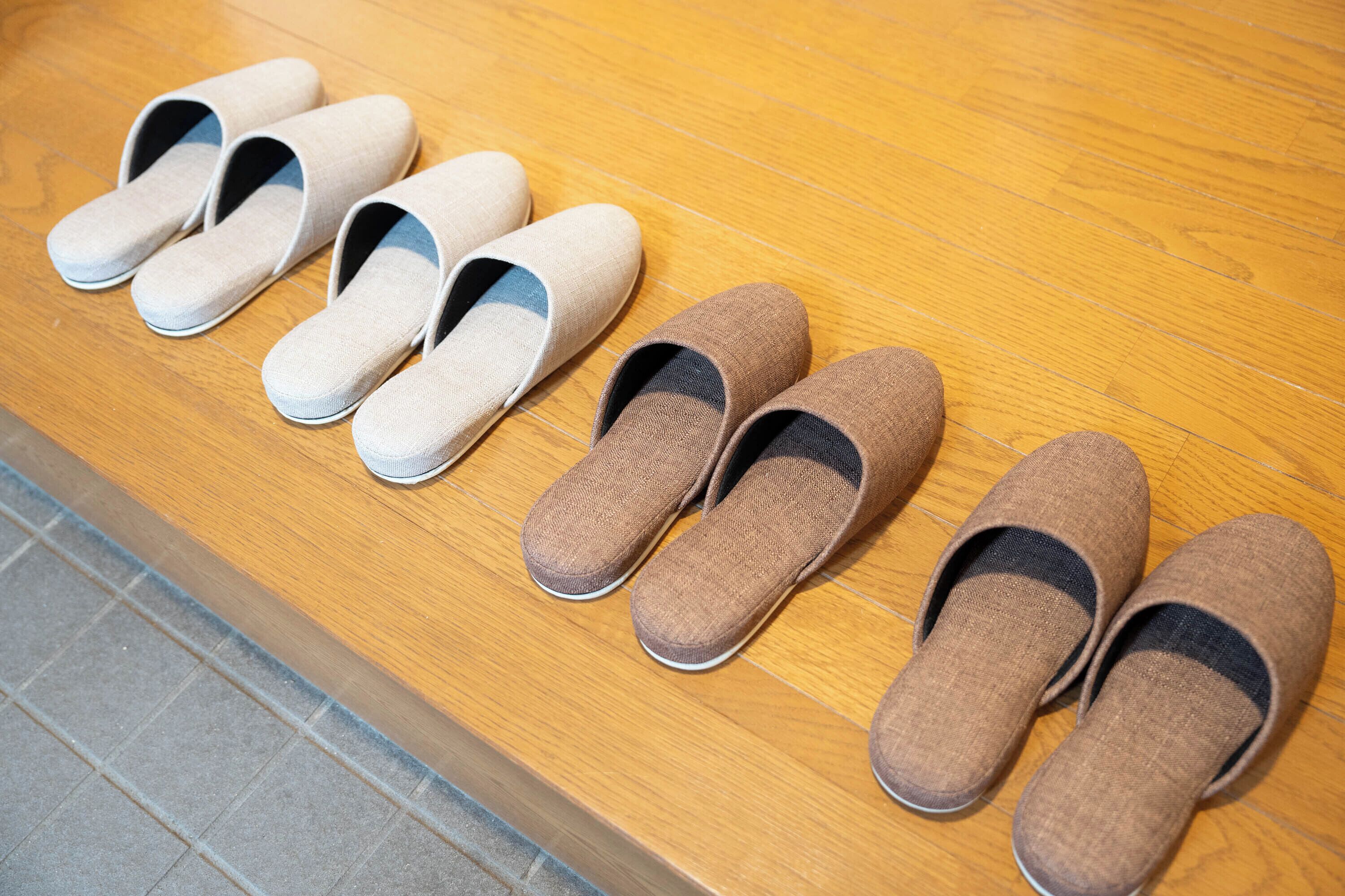 A row of slippers on a wooden floor.