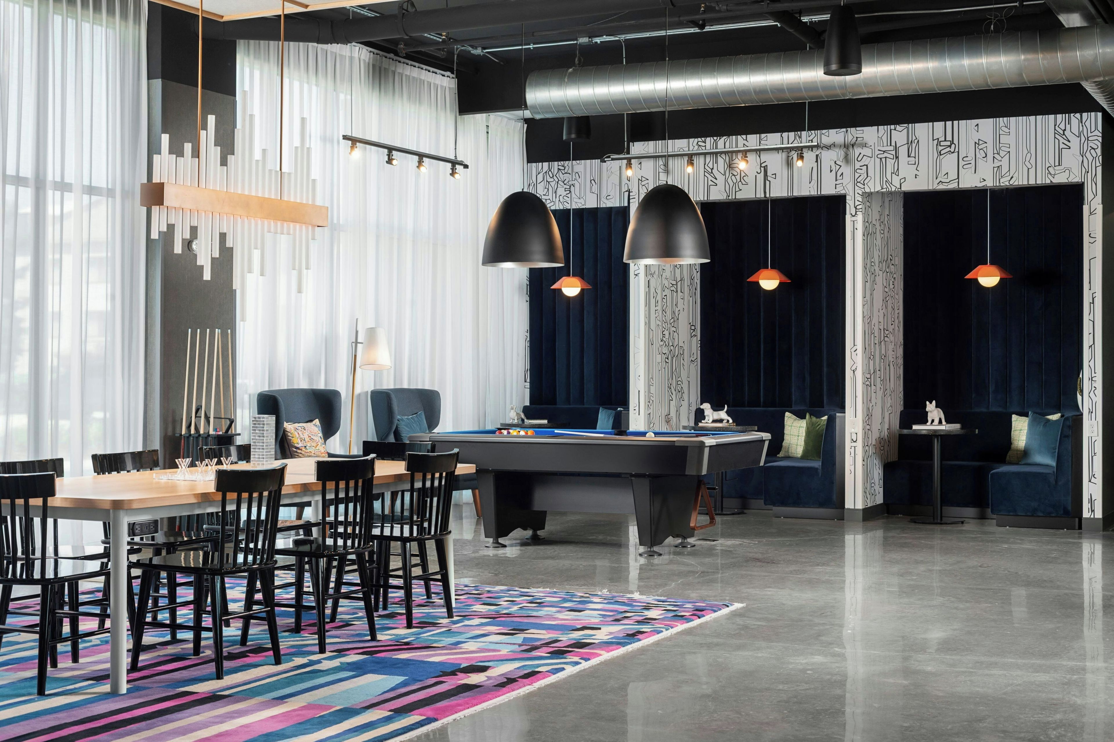 A modern lounge area with a pool table, comfortable seating, and a vibrant rug.