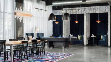 A modern lounge area with a pool table, comfortable seating, and a vibrant rug.