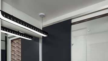 Casa de banho moderna com lavatório branco, toucador de tons escuros e um espelho grande.