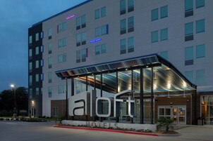 Un hotel moderno con un llamativo letrero 'a l o t e', amplias ventanas y una entrada cubierta.