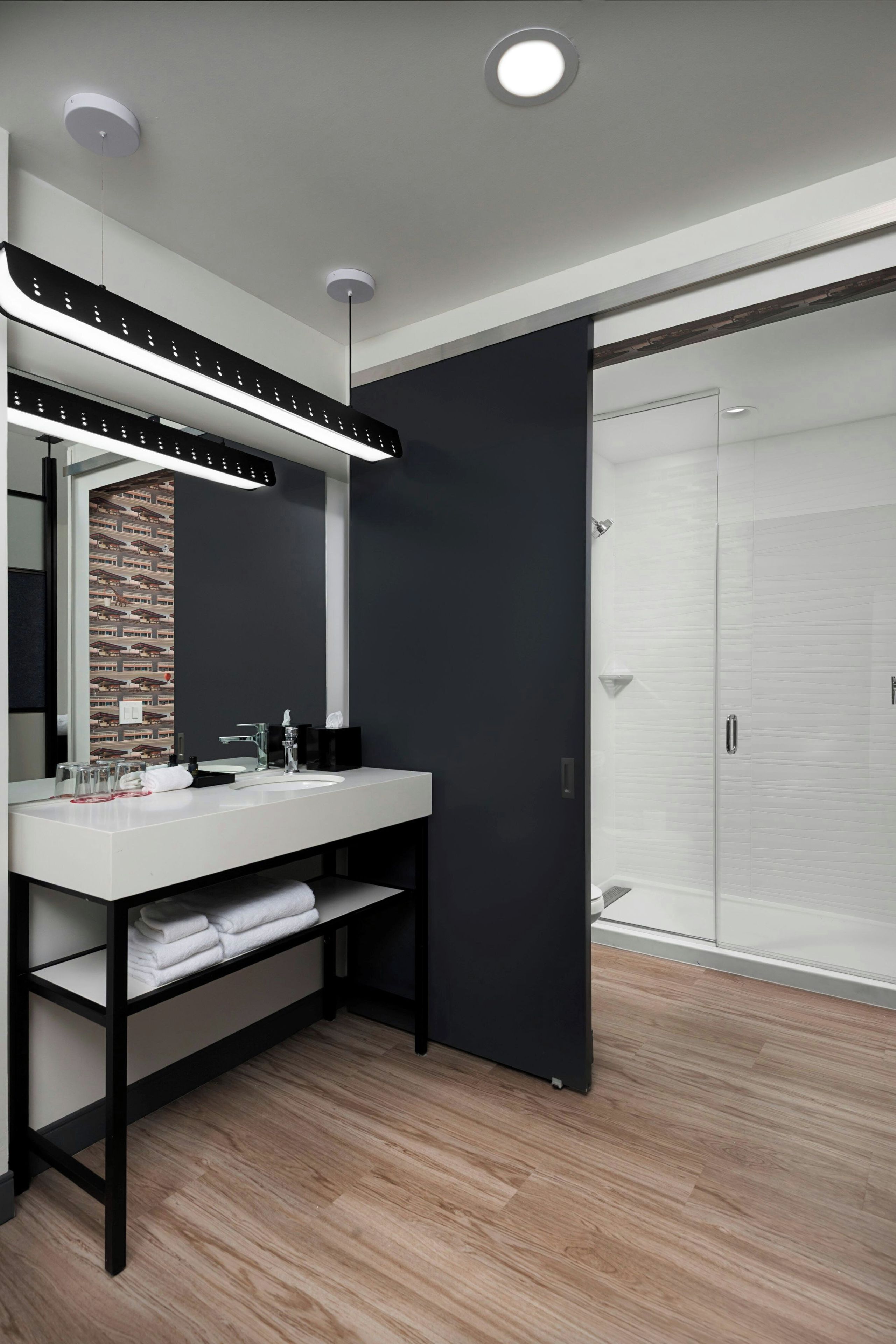 A modern bathroom with a white sink, black vanity, and a large mirror.