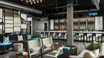 A modern bar area with a neon sign, bar stools, and a seating area with sofas and chairs.