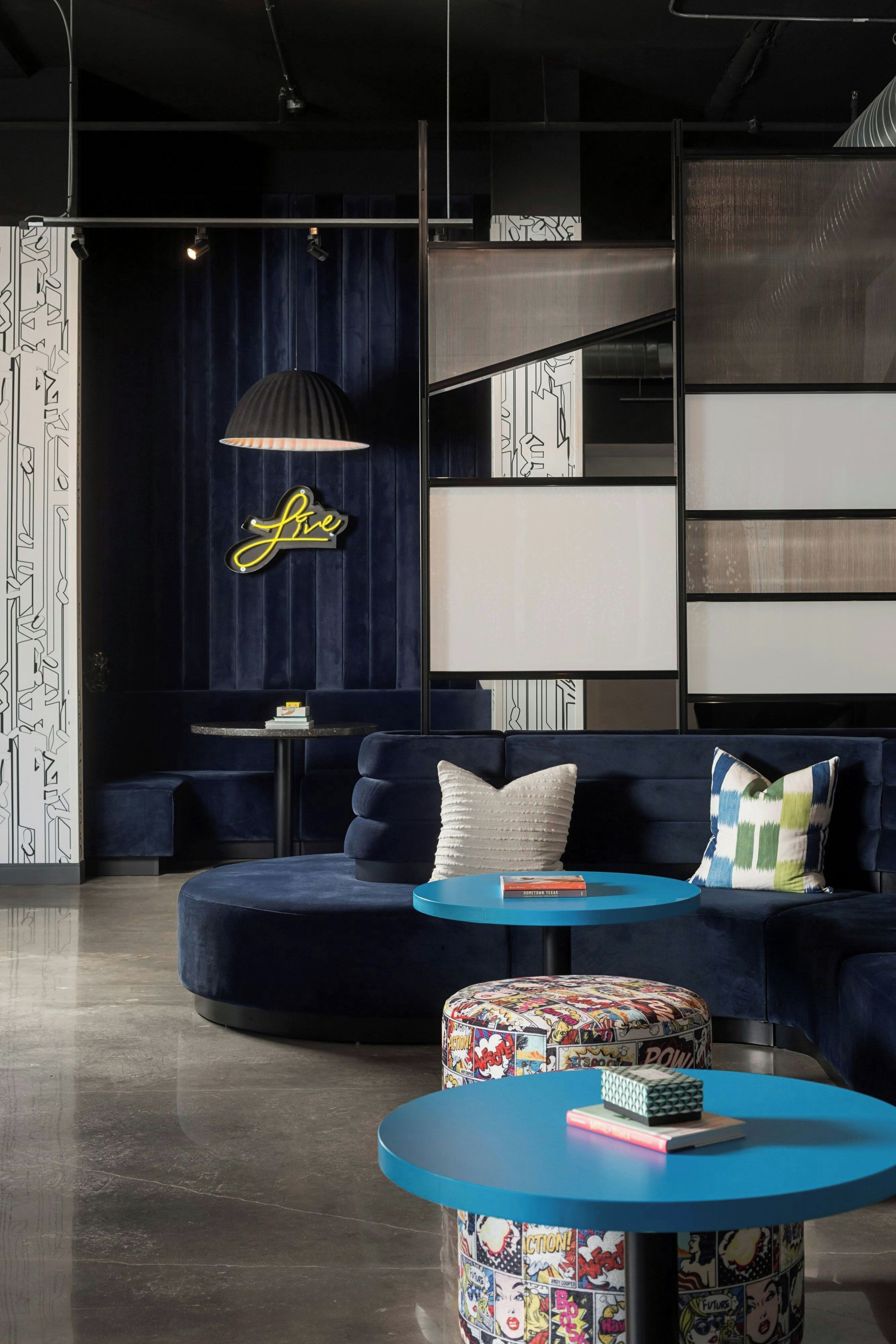 A modern lounge area with a blue sofa, a round table, and a decorative lamp.