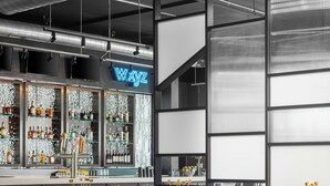 Un'area bar moderna con sedie rosse, un bancone bar con diversi liquori e un neon.