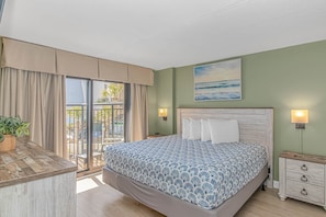 A bedroom with a bed, a nightstand, a dresser, a balcony with curtains, and a painting on the wall.