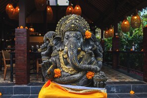 Une statue représentant une divinité éléphant, avec des détails complexes et des fleurs orange.