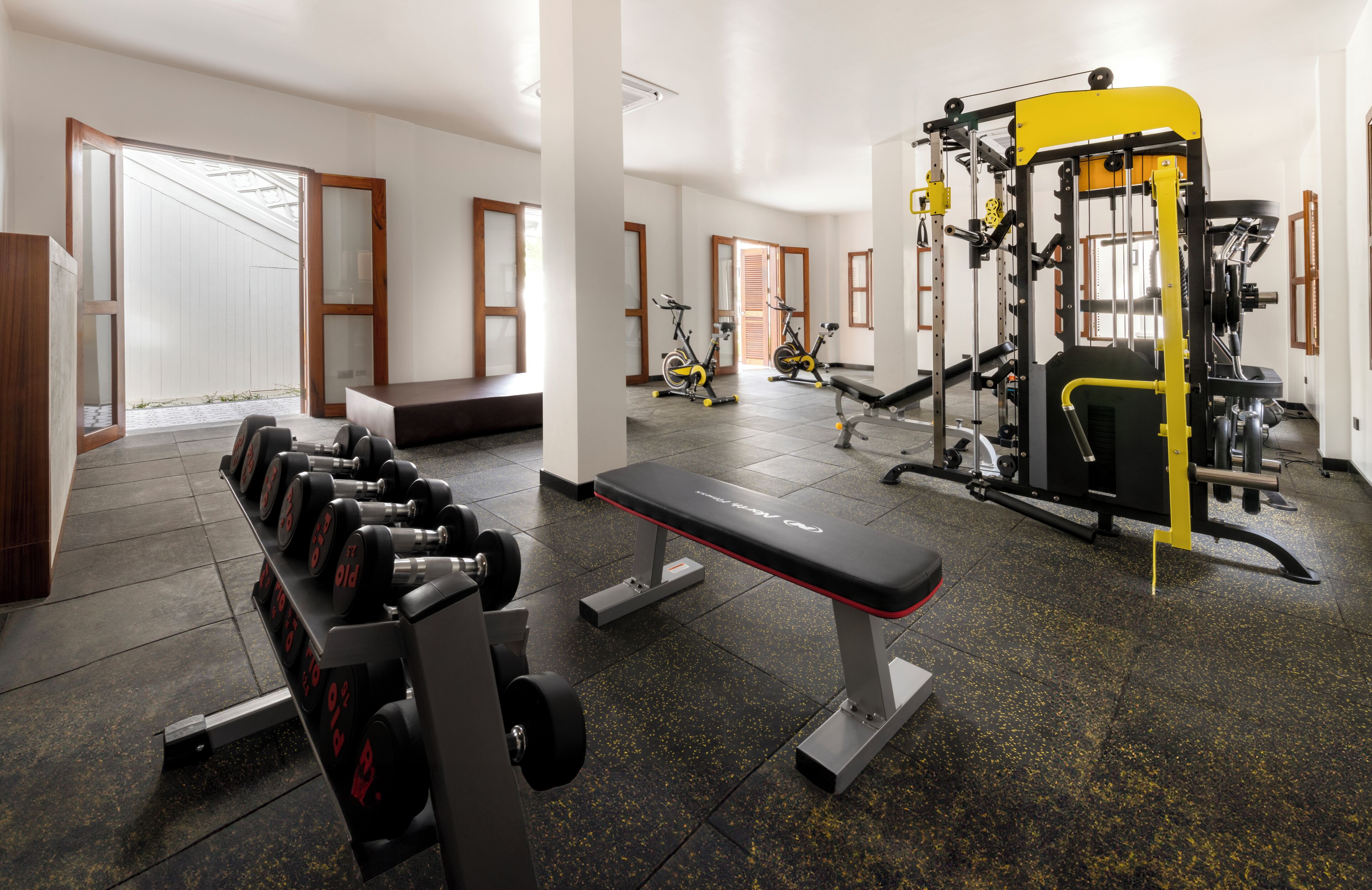A gym with exercise equipment, a bench, and a dumbbell rack.
